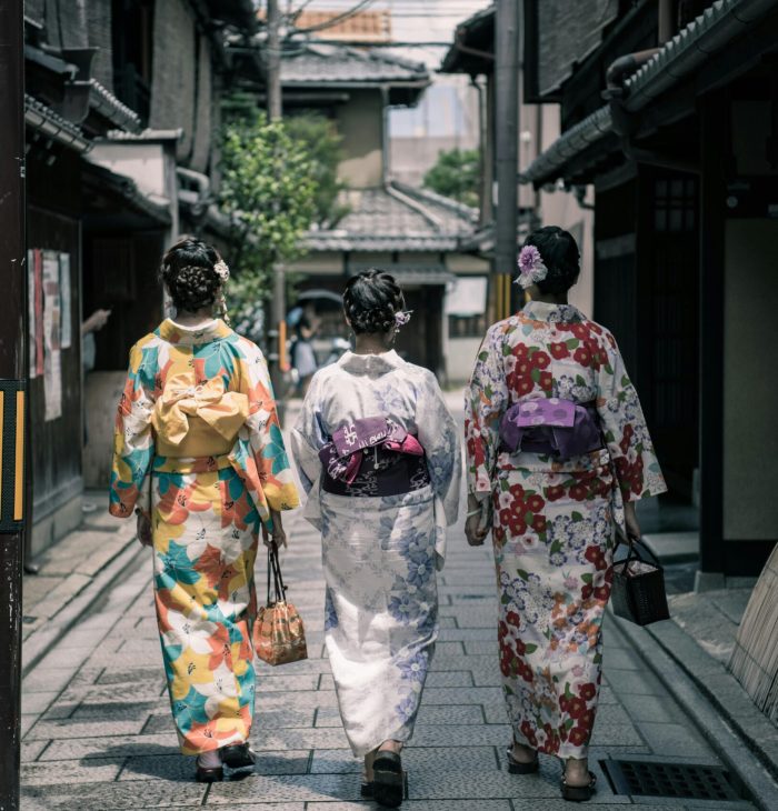 Three Geisha Walking Between Buildings