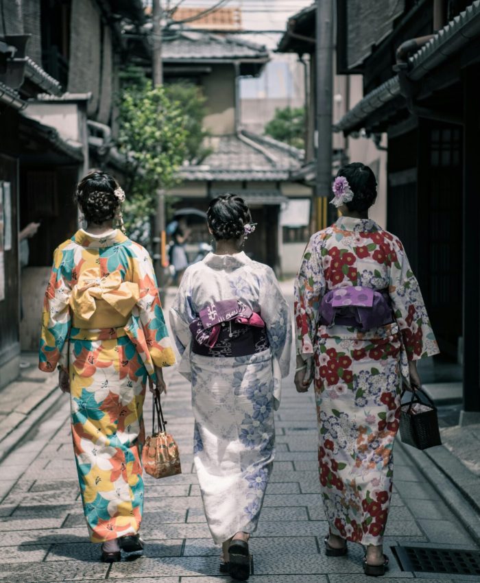 Three Geisha Walking Between Buildings